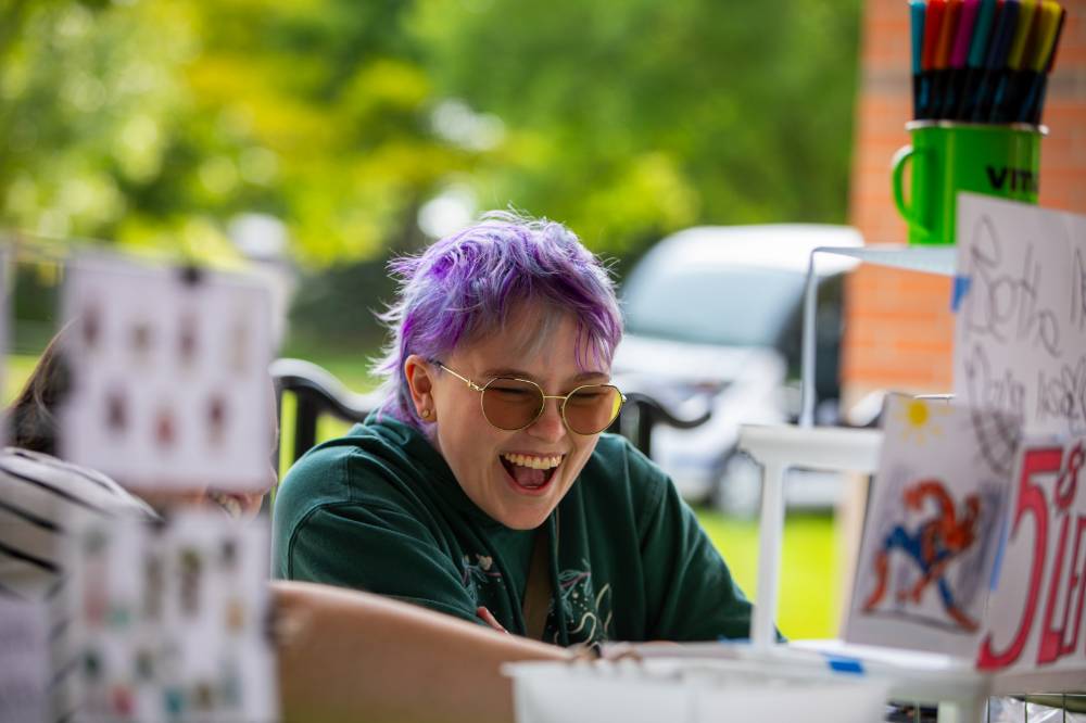 Student smiles while working a booth at Student Small Business Market.